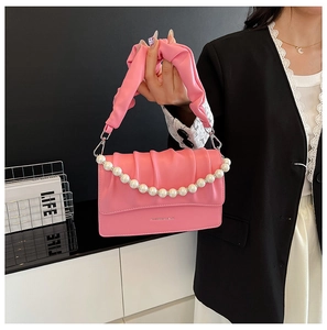 Close-up of pink pleated cloud bag featuring pearl chain strap and soft leather texture