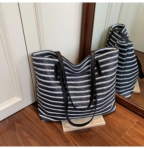Detailed texture of black and white striped woven tote bag with leather handles on floor