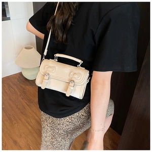 Detail of cream white crossbody bag featuring silver buckles and embossed textures