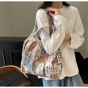 Artistic canvas tote bag with vintage calligraphy print shown on shoulder