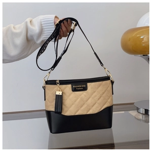Detail view of quilted beige canvas and black PU leather bucket bag with tassel