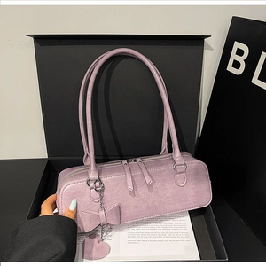 Détail du sac à l'épaule lilas effet croco avec pendentifs en forme de cœur et nœud