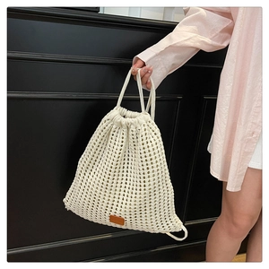 Detail of crochet drawstring bucket bag with hollow flower knit and leather label