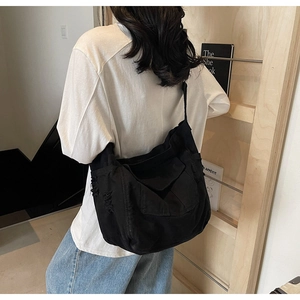 Detail of black canvas messenger bag featuring vintage distressed edges and frayed texture