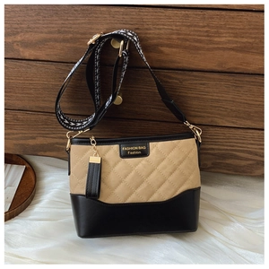 Detail of quilted khaki fabric and black leather base with fashion label and patterned strap