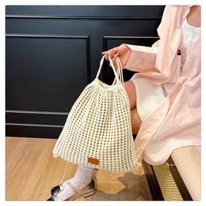 Close-up of cream knit bucket bag with floral hollow mesh pattern and leather logo detail