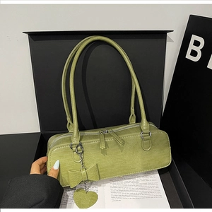 Gros plan du sac à bandoulière vert avocat gaufré croco avec pendentif en cœur