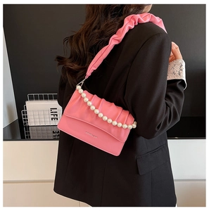 Detail view of pink pleated cloud bag with pearl chain accessory on model back