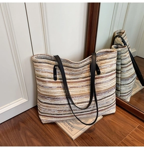 Close-up of the textured multicolor woven stripe pattern and black leather strap on a tote bag