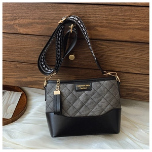 Detail of gray quilted crossbody bucket bag with mixed textures and wide patterned strap
