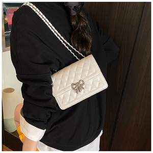 Détail du sac à bandoulière matelassé blanc crème avec un fermoir nœud en métal argenté