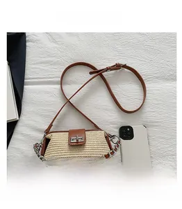 Detail view of woven straw handbag with brown leather trim and metal chain handle