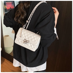 Détail du sac bandoulière blanc matelassé avec boucle nœud en argent et chaîne