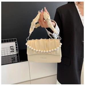 Close-up of beige ruched cloud bag with decorative large pearls and fashion text