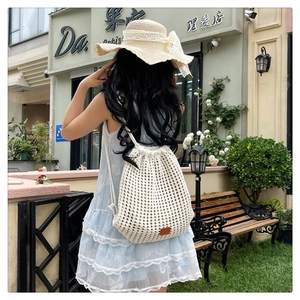 Detail of white knit drawstring backpack with crochet flower mesh and brown leather patch