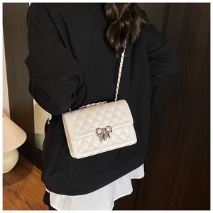 Détail du sac bandoulière blanc matelassé avec boucle nœud argentée et bandoulière chaîne