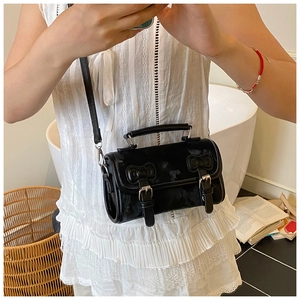 Detail of a black vintage mini crossbody bag with a cow print texture and silver buckles