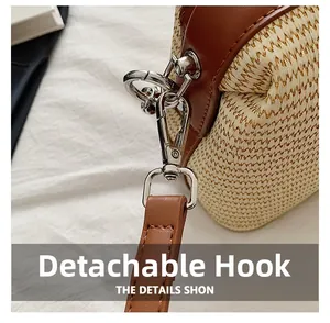 Close-up of detachable silver metal hook and leather strap on woven straw bag