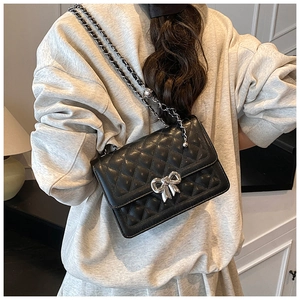 Détail du sac bandoulière matelassé noir avec boucle nœud argenté et chaîne en cuir