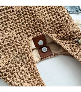 Detail of the magnetic buckle closure on a beige hollow out woven straw tote bag
