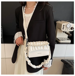 Detail of white pleated cloud bag with pearl chain strap and faux leather texture