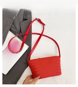 Detail of red woven intrecciato crossbody bag with matching leather shoulder strap