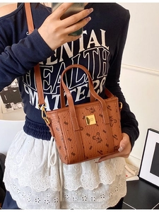 Brown leather handbag with bear prints and golden logo shown on a model