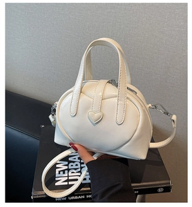 Detail view of cream mini Boston bag with heart relief and adjustable shoulder strap