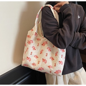 Close-up of white canvas tote bag featuring traditional red koi fish prints and wide straps