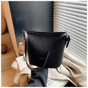 Detail of black litchi grain leather bucket bag with brand logo and cute bear pendant
