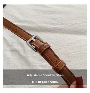 Detail of adjustable brown leather shoulder strap with silver metal buckle and fine stitching