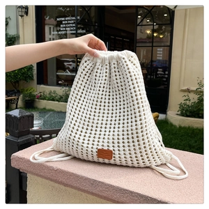 Detail of white crochet drawstring bucket backpack with hollow knit floral texture