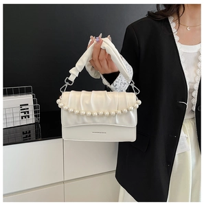 Close-up of white ruched cloud bag featuring decorative large pearls and fashion text
