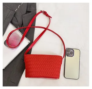 Red woven crossbody bag shown next to a smartphone to demonstrate the small size
