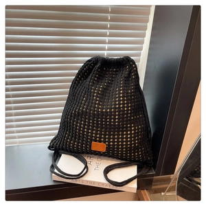 Detail of black crochet bucket backpack showing mesh knit texture and leather brand label