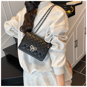 Détail du sac bandoulière matelassé noir avec boucle nœud argentée et bandoulière chaîne