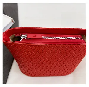 Close-up of smooth silver metal zipper and woven leather texture on a red handbag