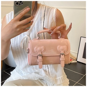 Detailed view of pink shoulder bag featuring decorative 3D bow elements and leather texture