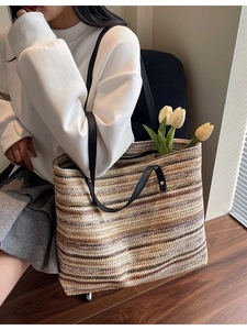 Striped woven straw tote bag with black leather shoulder straps for beach vacation