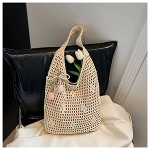 Detailed close-up of cream woven tote bag featuring pearl bow and tulip pendant details
