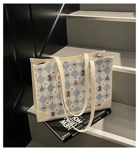Détail du sac cabas beige matelassé avec broderie d'ours et motif à carreaux
