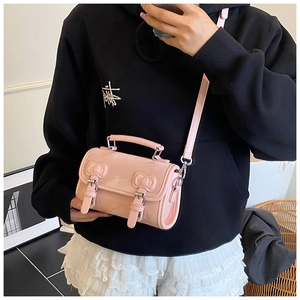Pink Boston bag with 3D bows and buckle straps shown held by a model in a casual setting