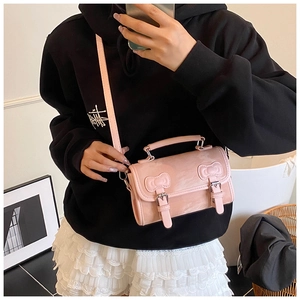 Detailed view of pink bow-knot crossbody bag with metal buckles and PU leather texture