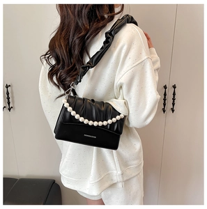 Detail of black pleated cloud bag with white pearl handle and long shoulder strap