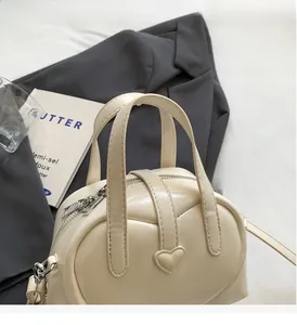 Close-up of cream leather Boston bag with heart-stitched pocket and dual handles
