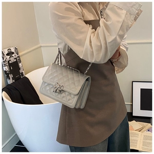 Détail du sac bandoulière argenté matelassé avec fermoir nœud et bandoulière chaîne