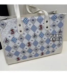Gros plan sur un tote bag matelassé blanc avec motif losange bleu et graphique d'ours