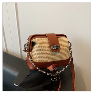 Detail of straw crossbody bag with leather trim, silver clasp, and chain strap