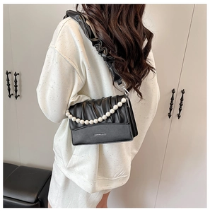 Detail of black pleated cloud bag featuring pearl chain strap and fashion logo