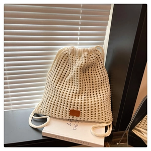 Detail showing the intricate crochet pattern and drawstring of the beige knit backpack